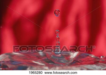 Stock Image - a water drop falling into water with a red background. Fotosearch