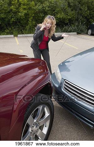 Stock Photo - a woman makes a phone call for help after she gets into a car accident; edmonton, alberta, canada. Fotosearch
