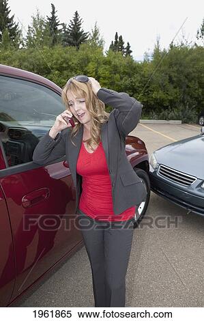 Stock Photography - a woman makes a phone call for help after she gets into a car accident; edmonton, alberta, canada. Fotosearch