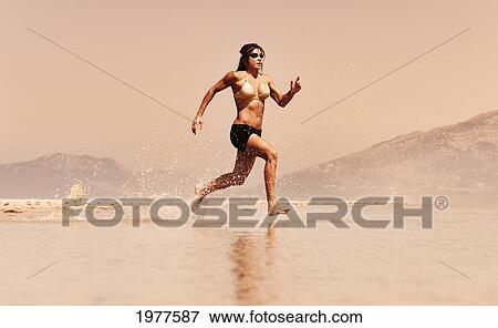 a woman runs in the shallow water along the beach; tarifa cadiz andalusia spain View Large Photo Image Stock Photo - a woman runs in the shallow water along the beach; tarifa cadiz andalusia spain. Fotosearch