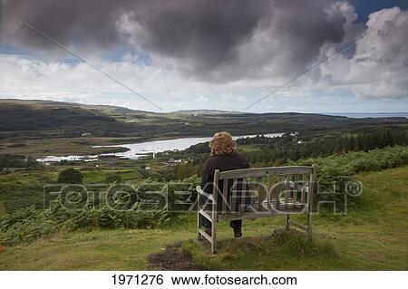 a woman sits on a wooden bench overlooking a landscape; isle of mull scotland View Large Photo Image Stock Photograph - a woman sits on a wooden bench overlooking a landscape; isle of mull scotland. Fotosearch
