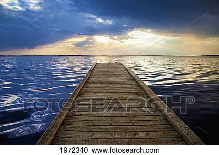 a wooden dock leads out to gull lake with the sunlight reflecting on the water at sunset; alberta canada View Large Photo Image Stock Image - a wooden dock leads out to gull lake with the sunlight reflecting on the water at sunset; alberta canada. Fotosearch