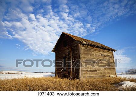 Stock Image - a wooden shed stands alone in a snow covered field; alberta canada. Fotosearch