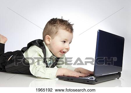 Stock Image - a young boy uses a laptop computer; edmonton alberta canada. Fotosearch