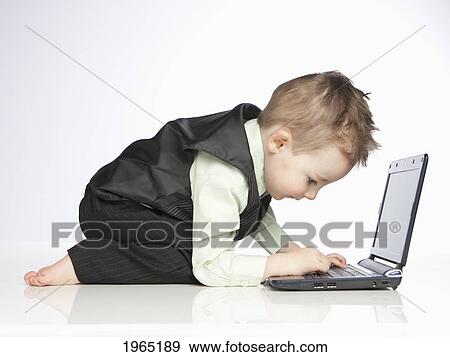 Stock Photo - a young boy uses a laptop computer; edmonton alberta canada. Fotosearch