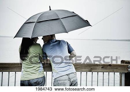 a young couple stands under an umbrella at the shoreline; bellingham washington united states of america View Large Photo Image Stock Image - a young couple stands under an umbrella at the shoreline; bellingham washington united states of america. Fotosearch
