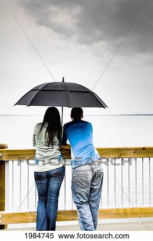 a young couple stands under an umbrella at the shoreline; bellingham washington united states of america View Large Photo Image Stock Photography - a young couple stands under an umbrella at the shoreline; bellingham washington united states of america. Fotosearch