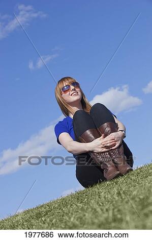 a young woman wearing sunglasses and sitting on the grass; edmonton alberta canada View Large Photo Image Stock Photograph - a young woman wearing sunglasses and sitting on the grass; edmonton alberta canada. Fotosearch