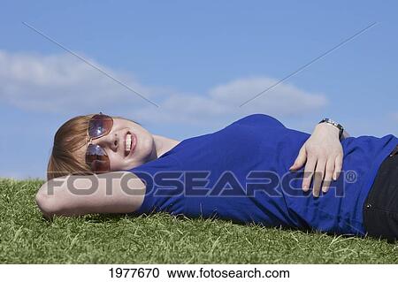 a young woman wearing sunglasses laying on the grass; edmonton alberta canada View Large Photo Image Stock Image - a young woman wearing sunglasses laying on the grass; edmonton alberta canada. Fotosearch