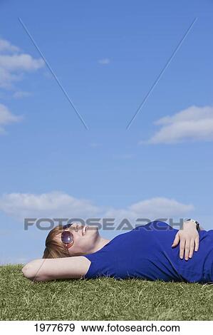 a young woman wearing sunglasses laying on the grass; edmonton alberta canada View Large Photo Image Stock Photo - a young woman wearing sunglasses laying on the grass; edmonton alberta canada. Fotosearch