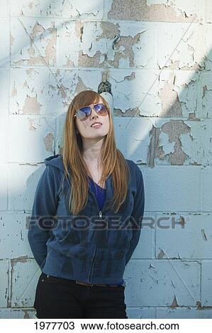 a young woman wearing sunglasses leaning against a wall; edmonton alberta canada View Large Photo Image Stock Image - a young woman wearing sunglasses leaning against a wall; edmonton alberta canada. Fotosearch