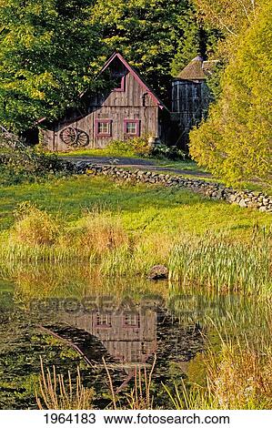 Stock Image - an old barn reflected in the pond water; ville de lac brome, quebec, canada. Fotosearch