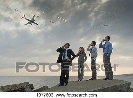 businessmen and a businesswoman talk on their phones while watching planes fly overhead; tarifa cadiz andalusia spain View Large Photo Image Stock Image - businessmen and a businesswoman talk on their phones while watching planes fly overhead; tarifa cadiz andalusia spain. Fotosearch