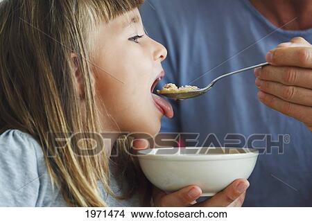 child being spoon fed food from a bowl by her father; spain View Large Photo Image Picture - child being spoon fed food from a bowl by her father; spain. Fotosearch