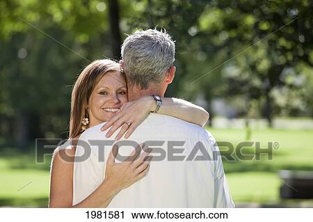 Stock Image - couple embracing in the park; edmonton alberta canada. Fotosearch
