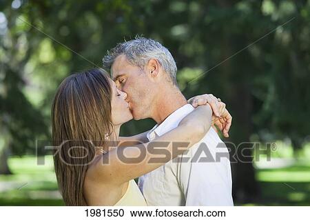 Stock Image - couple kissing in the park; edmonton alberta canada. Fotosearch