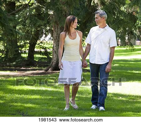 couple walking in park together holding hands; edmonton alberta canada View Large Photo Image Stock Image - couple walking in park together holding hands; edmonton alberta canada. Fotosearch