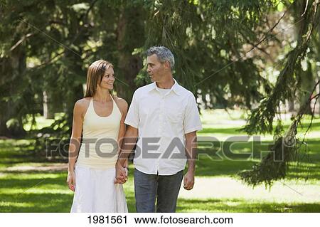 Stock Image - couple walking in park together holding hands; edmonton alberta canada. Fotosearch