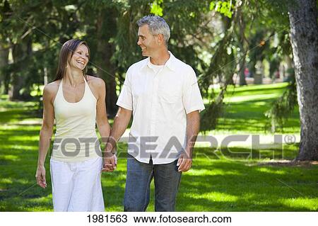 couple walking in park together holding hands; edmonton alberta canada View Large Photo Image Stock Image - couple walking in park together holding hands; edmonton alberta canada. Fotosearch