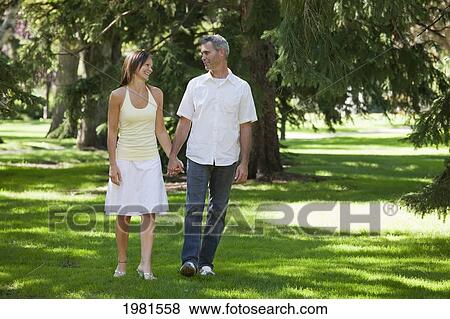 Stock Photo - couple walking in park together holding hands; edmonton alberta canada. Fotosearch