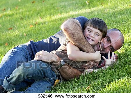 father and son laying on the grass in an embrace in the park; beaumont alberta canada View Large Photo Image Stock Photograph - father and son laying on the grass in an embrace in the park; beaumont alberta canada. Fotosearch