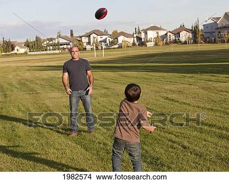 father and son playing football in a park; beaumont alberta canada View Large Photo Image Picture - father and son playing football in a park; beaumont alberta canada. Fotosearch