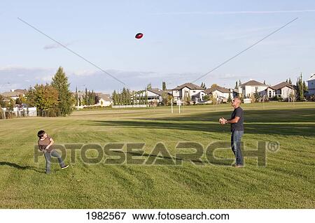 father and son playing football in a park; beaumont alberta canada View Large Photo Image Stock Photo - father and son playing football in a park; beaumont alberta canada. Fotosearch