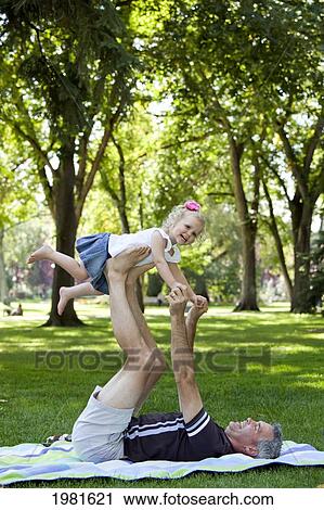 father lifting daughter up on his legs in the park; edmonton alberta canada View Large Photo Image Stock Image - father lifting daughter up on his legs in the park; edmonton alberta canada. Fotosearch