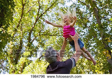 father throwing toddler daughter in the air in a park; edmonton alberta canada View Large Photo Image Stock Photograph - father throwing toddler daughter in the air in a park; edmonton alberta canada. Fotosearch