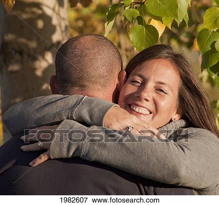 Stock Photo - husband and wife in an embrace in a park; beaumont alberta canada. Fotosearch
