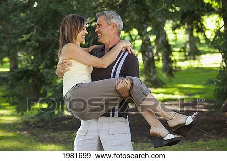 Stock Photo - husband picking up his wife in a park; edmonton alberta canada. Fotosearch