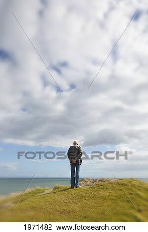 man standing alone on a hill staring at the ocean at inchydoney beach near clonakilty; county cork ireland View Large Photo Image Stock Image - man standing alone on a hill staring at the ocean at inchydoney beach near clonakilty; county cork ireland. Fotosearch