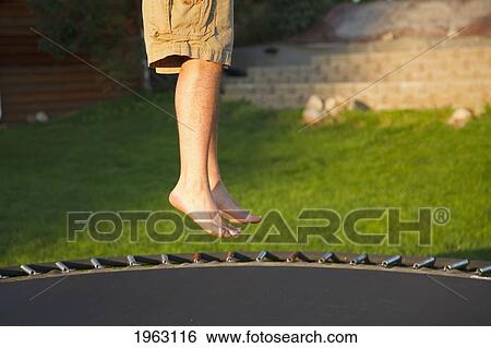 Stock Photograph - man's legs jumping on a trampoline; ferndale, washington, united states of america. Fotosearch