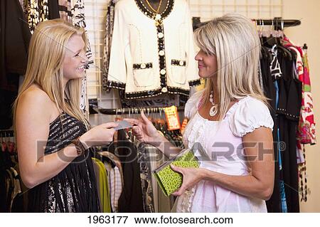 Stock Photo - mother buying daughter a dress at a boutique; edmonton, alberta, canada. Fotosearch