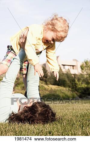 Picture - mother plays with young daughter in grass; bellingham washington united states of america. Fotosearch