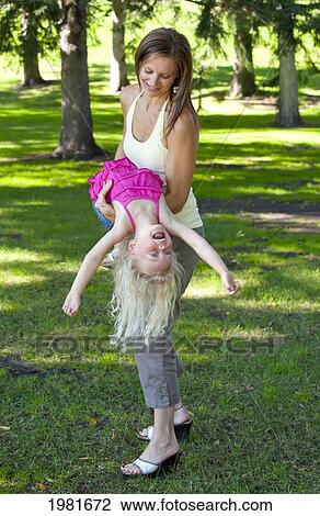Stock Image - mother swinging daughter around in the park; edmonton alberta canada. Fotosearch