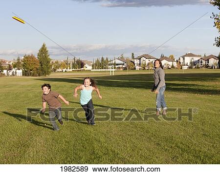 Stock Photo - mother throwing flying disc to children in a park; beaumont alberta canada. Fotosearch