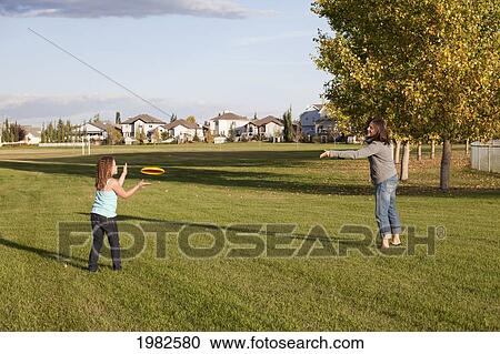 Stock Image - mother throwing flying disc to daughter in a park; beaumont alberta canada. Fotosearch