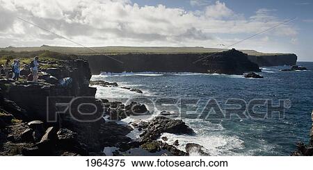 Stock Photography - people standing on a rock ledge along the coast of espanola island; galapagos, equador. Fotosearch