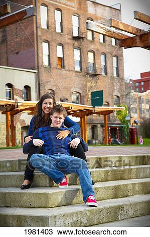 Stock Image - portrait of a young couple sitting on steps; bellingham washington united states of america. Fotosearch