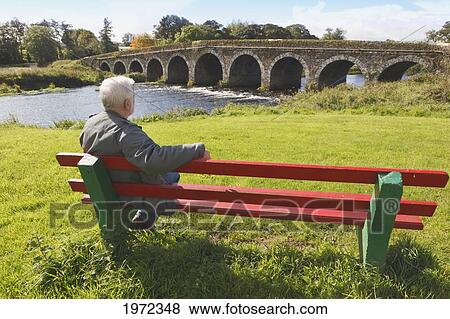 retired man on a public bench looking at a bridge over bandon river; ballineen county cork ireland View Large Photo Image Stock Photo - retired man on a public bench looking at a bridge over bandon river; ballineen county cork ireland. Fotosearch