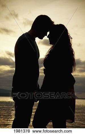 silhouette of a couple standing at the water's edge; bellingham washington united states of america View Large Photo Image Stock Photo - silhouette of a couple standing at the water's edge; bellingham washington united states of america. Fotosearch