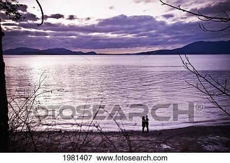 Stock Photo - silhouette of a couple standing at the water's edge; bellingham washington united states of america. Fotosearch