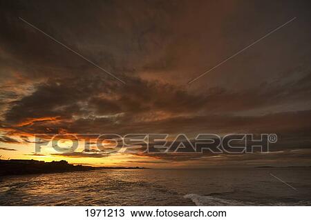 Stock Image - sunset over the ocean; bamburgh england. Fotosearch