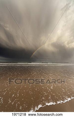 tide coming up onto the beach with a rainbow in the clouds; bamburgh england View Large Photo Image Stock Photo - tide coming up onto the beach with a rainbow in the clouds; bamburgh england. Fotosearch