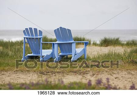 Stock Photo - two blue adirondack chairs on a grassy beach; oregon united states of america. Fotosearch
