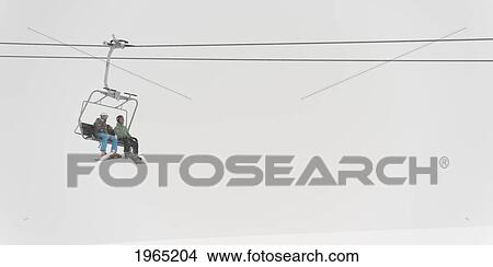 two people riding a chairlift at a ski resort; whistler british columbia canada View Large Photo Image Picture - two people riding a chairlift at a ski resort; whistler british columbia canada. Fotosearch