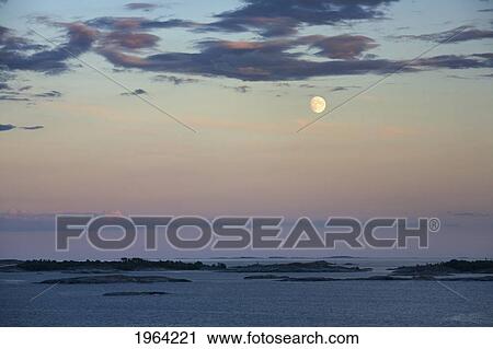 Stock Image - waterways through the islands and a full moon at sunset; stockholm, sweden. Fotosearch