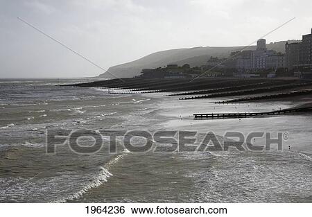 Stock Photograph - waves coming into shore and buildings along the coast; eastbourne, sussex, england. Fotosearch