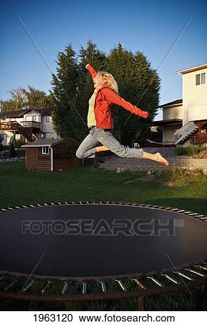Stock Image - woman jumps on a trampoline; ferndale, washington, united states of america. Fotosearch